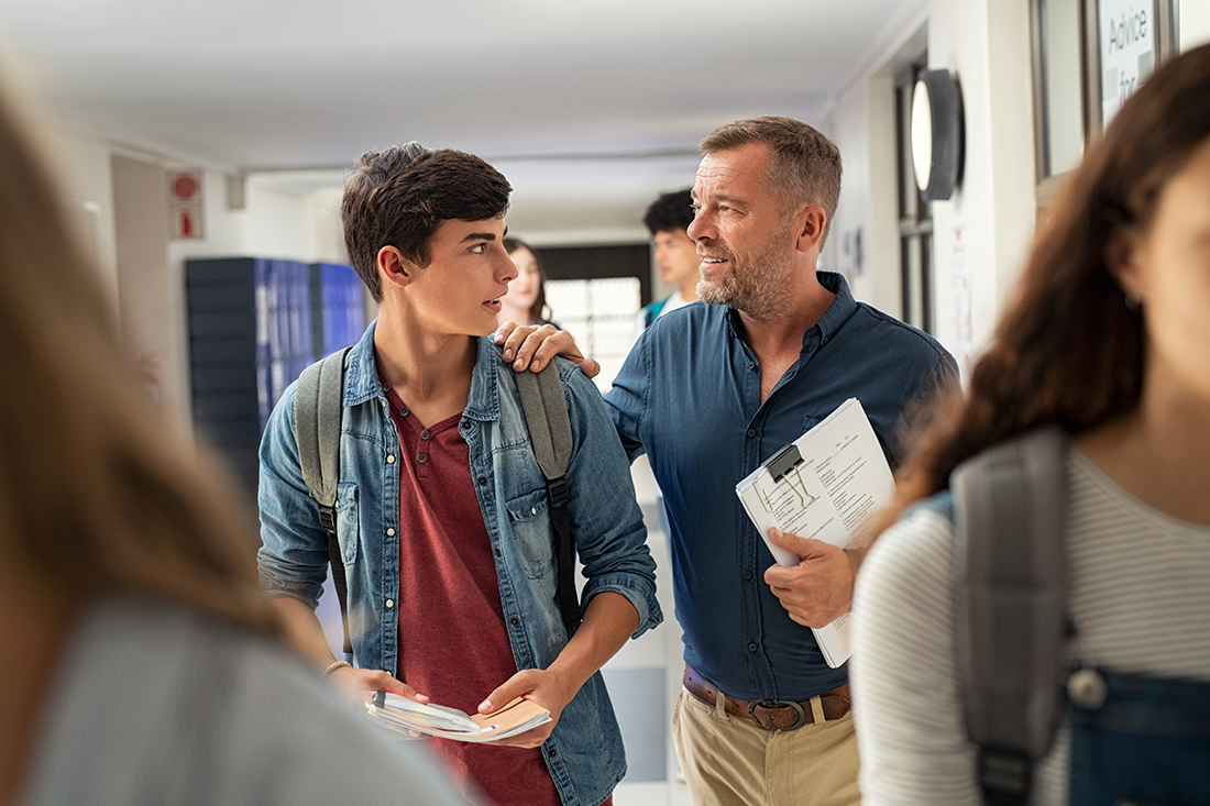 Male supportive teacher and student walking down the hall
